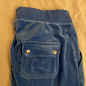 Blåa juicy byxor - Säljer dessa blåa juicy byxor då de är lite för stora. De är rätt använda så de är lite bleka i färgen men är ändå i bra skick.