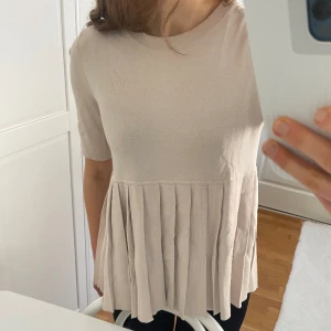 Beige Topp från COS - Säljer denna beiga peplum/volang topp från COS i storlek XS. Bra skicka förutom lite sminkmärke på halsringen som syns på bild nr.3. 