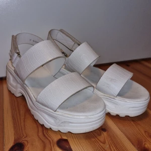 Vita platåsandaler  - Vita sandaler från Attitude i bra skick. Justerbart kardborrespänne vid hälen. Perfekta sommarskor!Säljer för att de blivit för små.