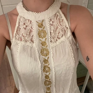 Spets blus  - Vit blus med guldiga och spets detaljer! Fint australiskt märke! Den är halvt öppen i ryggen! Helt otroligt fin! En knapp saknas men man kan lätt du dit en ny, man kan även behöva fixa till den knappen som finns kvar! Men den går att knäppa! 
