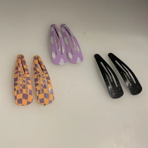  hårspännen  -  svarta glittriga hårspännen orange tja med lite lila och lilla med små vita moln på jättefint och Kan du ta bort luggen