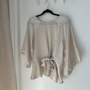 Beige 👚  - Blus från Bubbleroom i storlek 36. Glansigt material. Sparsamt använd. 