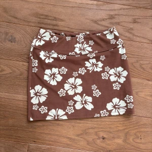 Sommarkjol 💕 - Brun kort sommarkjol från H&M med hibiskusblom-mönster i en väldigt ljus-mint/turkos färg  storlek xxs   använd fåtal gånger   Inga fläckar eller skador på tyget  Mindre pass form men stretchigt material  Säljs eftersom jag inte använder den ofta 