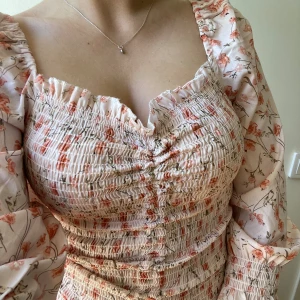 Blommig sommarklänning  - Så fin blommig klänning som aldrig har kommit till användning. Går att spänna banden framtill för att få mer ”scrunch”.