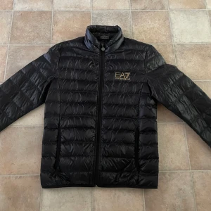 Ea7 jacka  - En perfekt jacka till lite kyligare kvällar/dagar. En svart ea7 jacka med guldig logga. Använd 1 gång så är därför i ny skick. Hör av er vid frågor. Priset går att diskutera vid snabb affär!