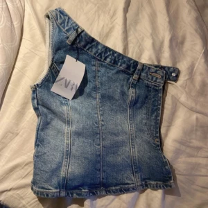 One shoulder jeanstopp! - Skitsnygg jeans topp fårn zara! Aldrig använd, prislappen kvar! Storlek xs men skulle säga att den passar en s också! Nypris 359 kr, och köpt för 1,5 år sedan så osäker om den finns kvar.