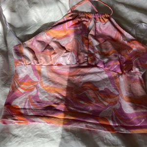Spräcklig topp - skitsnygg spräcklig sommartopp med omlott band i ryggen. ”öppen” mellan brösten. strl m men skulle säga att den mer är som en blandning av s och m då den inte är jättestretchig. använd fåtal gånger, inga defekter. 