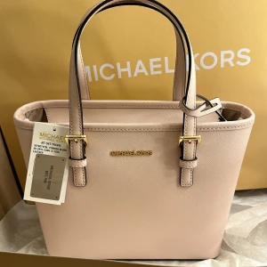 Michael kors väska - En liten Michael kors väska väldigt praktisk,  som även har band man kan ha till. Aldrig använt då har fått den i present, så tyvärr inget kvitto på det men prislapp finns kvar. 