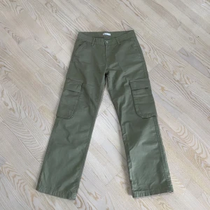 Low waist cargo jeans  - Säljer ett par low waisted gröna cargo jeans i storlek 34 från Gina Tricot. De är väldigt bekväma och har bara använts 1-2 gånger, så de är i utmärkt skick. Jeansen är jättefina och perfekta för att skapa en trendig och avslappnad look.