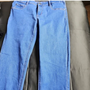 Raka stretch jeans - Nya Mjuka jeans i strl L men skulle nog säga att dom är mer som M skullenog säga att färgen är mellanblå. Dragkedja och knappar. Katt finns I hemmet