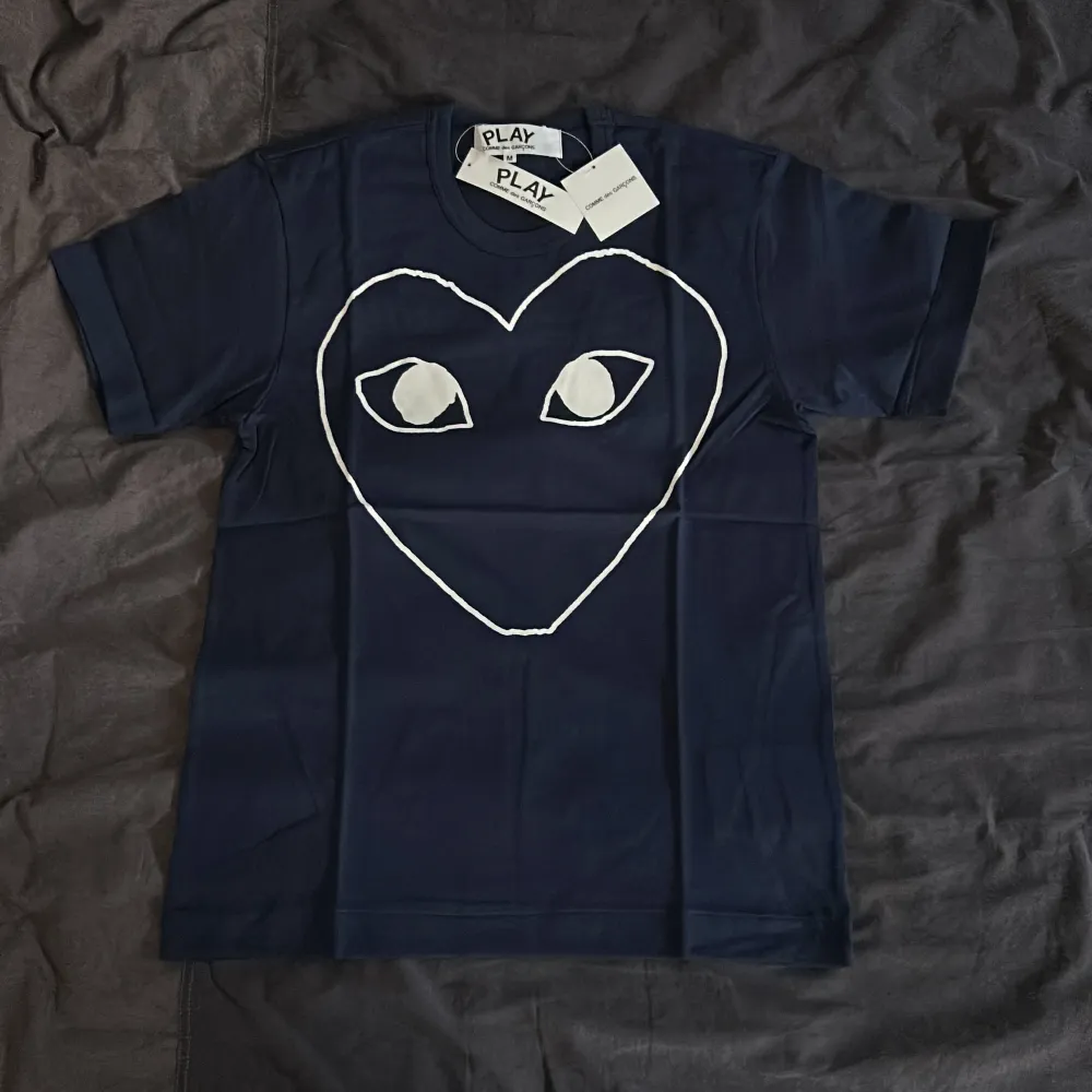Mörkblå Comme des Garçons tshirt helt oanvänd. Nypris ligger på strax över 1000kr, säljes då den inte passar och blir dyrt med tullkostnader att skicka tillbaka. . T-shirts.