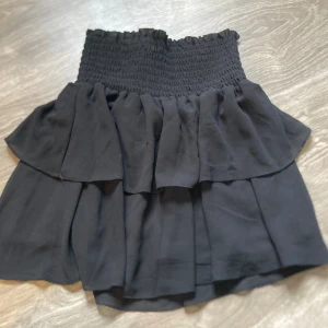 Kjol strl S Chelsea  - Svart kjol strl S från Chelsea. Volanger och underkjol, så kjolen är inte genomskinlig. Material: 100% polyester  Mycket fint skick, använd nägon gång bara så kjolen är som ny. 