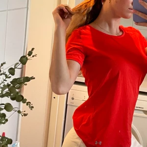 Träningströja Under Armour - Nyskick. Funktions t-shirt från under armour i aprikos/orange-röd fin färg.