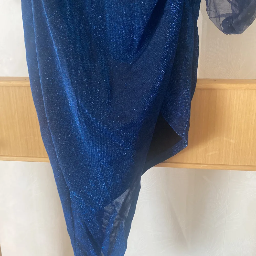 Festlig knälång klänning med slits. Väldigt fint glitter på som inte skaver och är i form av korsett vid bröstkuporna med genomskinliga armar. Väldigt bra skick, använd endast 1 gång. . Mekot.