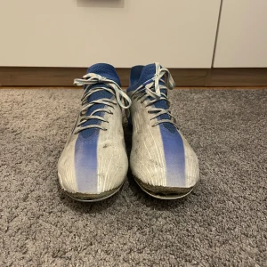 Adidas Speedflow - Ett par Adidas Speedflow vit/blå. Storlek 42. Välanvända och har tappat lite i fronten med fungerar väldigt väl att spela i! Lite smutsiga men går att tvätta bort. Därav priset Nypris: 2299  Hör gärna av dig om du har frågor!