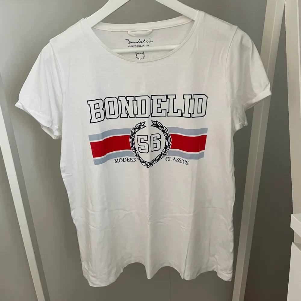 Vit T-shirt från Bondelid med tryck, i storlek M. Använd fåtal gånger så mycket bra skick✨ Köparen står för frakten, kan mötas upp i Kalmar!. T-shirts.