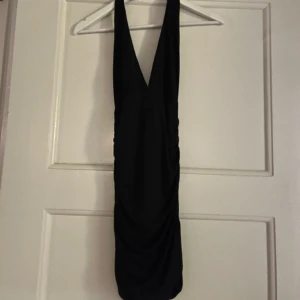 Tajt klänning  - Supersnygg tajt svart klänning som är öppen i ryggen och halterneck. Är väldigt stretchig och har en djup urringning. 