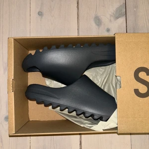 Yeezy slides ’slate gray’. - Säljer ett par yeezy slides i nyskick helt oanvända. Köpta på adidas CONFIRMED, kvitto och box finns kvar. Passar även storlekarna 41-43. Skriv om du har några frågor!