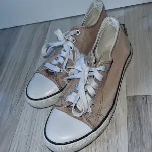 Ett par beige sneakers med vita tår och snören. Skorna har en vit sula med svart rand. Från keepers, i stl 36 och innermått ca 22 cm.