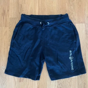 Svarta Shorts Sail Racing - Svarta shorts av märket Sail Racing. INTE marinblåa som bilden ser ut att visa. Storlek 160, skulle bedöma att en XS bör kunna bära dem eller någon med smala ben. Väldigt sparsamt använda. Tillverkade i tjockt och kvalitativt bomull. 