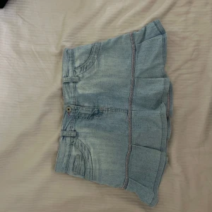 Ljusblå jeansshorts - Ett par ljusblå jeansshorts med fickor fram och bak. Shortsen har en knapp och dragkedja framtill samt dekorativa sömmar.