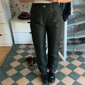 Ganni byxor - Säljer mina fina byxor från Ganni i glansigt grönt material! Byxorna passar så bra till både fest och vardags!   Har använts mycket av mig och några trådar har gått på baksidan  Strl 34 och passar mig bra som vanligtvis är en xs/s!  Säljer för 400 kr