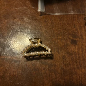 Guldfärgad hårklämma med pärlor - En guldfärgad hårklämma dekorerad med vita pärlor