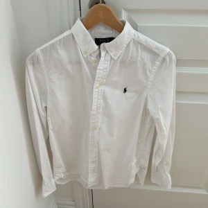 Ralph Lauren Skjorta - Säljer en riktig nice ralph lauren skjorta i storlek 16 år men skulle nog säga att den passar 14år bättre den är slim och för liten för mig nu använt en gång. Nypris 1600kr mitt pris 600kr perfa nu på sommaren 