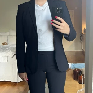 Hugo boss kostym marinblå, kjol, kavaj, kjol dräkt - En mörkblå kostym i fint skick i 3 delar från Hugo boss i storlek 36. Säljes då den har blivit något liten på mig, annars mycket bra kvalitet och håller länge.