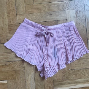 Pyjamasshorts, hunkemöller - Plisserade pyjamasshorts från hunkemöller. Strl S. Gammelrosa färg. Den svarta färgen är lappen som syns igenom, ingen fläck.