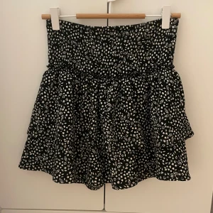 Svart och vit volangkjol  - Superfina volangkjol med små vita blommor på! Super praktiskt då det finns ett par shorts inbyggda under kjolen! Superfint skick och märket är Zara. Står i kjolen att storleken är 13-14 år men skulle säga att det passar XS/S.
