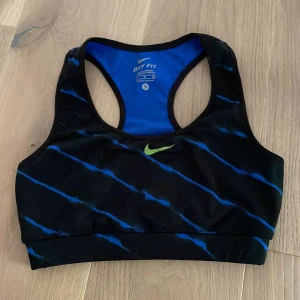 Sport topp Nike  - Svart sporttopp från Nike med blåa detaljer, knappt använd men säljer då den var för stor. Toppen är i storlek S och sitter som resten av Nikes sporttoppar ☀️