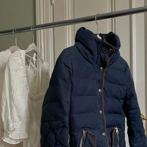 Snygg marinblå jacka - Fin mörkblå jacka med bruna och guldiga accenter och snygg krage. Från Vero Moda och i gott skick, perfekt till hösten.