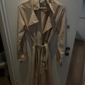 Vår-Kappa i beige - Vårig kappa i beige. Knappt använd. Runt material som är perfekt till vår och sommar 