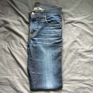 Mörkblå Nudie Jeans med extremt snygg tvätt i felfritt skick förutom att läderflärpen i bak är lite urtvättad, märks dock ej vid användning. Passform regular/slim men åt det slim hållet (modellen heter Slim Jim). Nypris runt 1500kr.