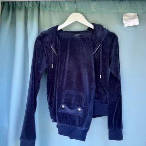 Tracksuit Juicy Couture  - Väldigt fin och skön tracksuit från Juicy Couture i fin marinblå färg. Köpt från Nelly.com så nypris 2500 kr. Den är flitigt använd, saknar ett snöre i byxorna och har tappat lite färg på metallerna, men inget som märks. Tröja och byxor är XS. 