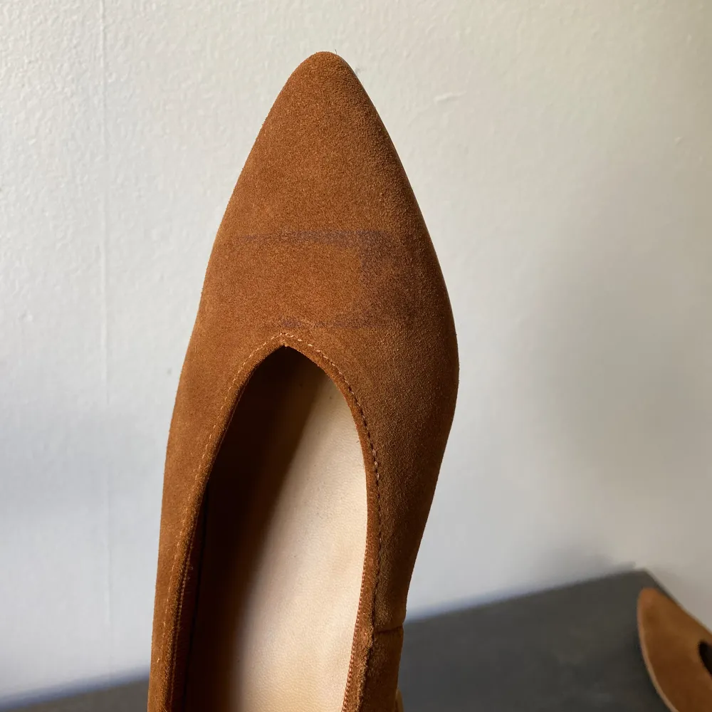 Pumps i klassisk modell i mjuk mocka med bred, klädd klack och v-ringad fotöppning. Textilfodrad insida. Klackhöjd ca 5,5 cm i stl 37. -Slitning på vänster sko framme vid tån -Använda endast en gång -Nypris 499:- . Kengät.