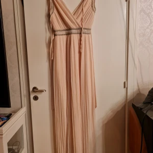 Lång finklänning från Tfnc London  - Lång finklänning i färgen ljus korall, det är i bra skick är i storlek uk12 vilket motsvarar storlek 40 enligt deras hemsida och är av märket Tfnc London   