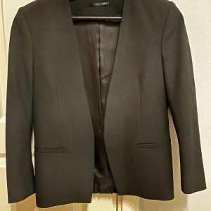 Filippa K kavaj oanvänd - Superfin svart blazer. Helt oanvänd. Funkar även som en finare kofta då den kan både dressas upp och ner. Säljer pga liten storlek.   Yttermaterialet: 68% polyester  29% Viskos 3% Elastan Innermaterial:  50% Acetat 50% Viskos