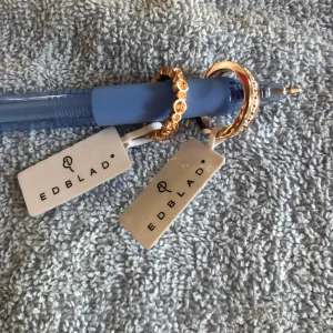 Edblad - Edblad rosé gold stl :s / 16mm Den har stenar runt hela ringen. Den är helt oanvänd.  Ring m små blommor med stenar i, runt hela ringen.  Färgen är rosé gold stl: xs / 16mm Den är oanvänd  Pris 99 kr / st