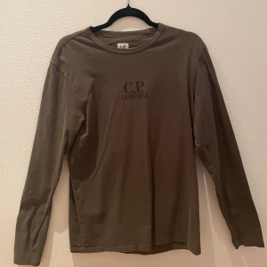 CP company tröja - Långärmad T-shirt i size M av märket CP Company. Tröjan är olivgrön och använd max 5 ggr.