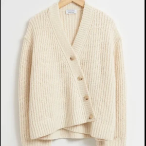 Assymetrisk stickad kofta vit - populära koftan från otherstories, jag säljer den vita o sista bilden är min egen! Inga defekter (fläcken är på spegeln) 🙈🙈🙈Nypris 1300 o helt slutsåld 💗