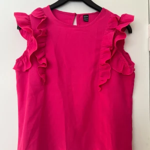 rosa topp med volang - rosa topp med volanger från shein i storlek s, ser mörk ut men kan lösa bättre bild, nästan aldrig använd, bara några gånger, säljer då den inte kommer till användning, inga tecken på användning! skriv för fler bilder, köparen står för frakten
