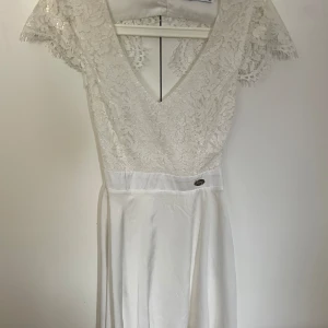 Vit klänning  - Säljer denna jättefina vita klänning från bubbleroom då den tyvärr ej passar längre. Storlek XS. Fint skick, använd endast 2 gånger på skolavslutningar. Öppen i ryggen & stängs med två knappar i nacken, spets upptill & silkes nedtill💗💗💗