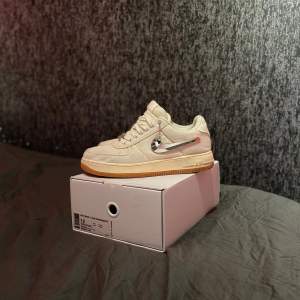 Säljer ett par Nike Air Force 1 Travis Scott sneakers i nyskick. Skorna är vita med en spegelblank Swoosh-logga på sidan och en gummisula. Är i storlek 46. Perfekta för både vardag och fest! den är dock lite skadad vid swoosh-logan men annars är den i en suverän skick