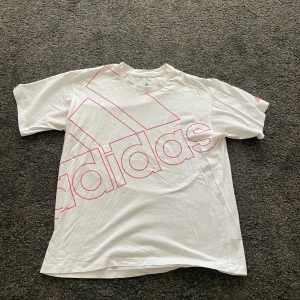 Vit t-shirt - En vit oversized adidas t-shirt med rosa tryck. Skön att träna i. Använd ett fåtal gånger. 