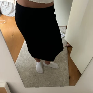 Svart ribbad kjol - Säljer en svart ribbad kjol i storlek S. Kjolen är tight och har en enkel, stilren design som passar perfekt till både vardag och fest. Den är knälång och gjord i ett stretchigt material som gör den bekväm att bära. Perfekt för höst och vinter!