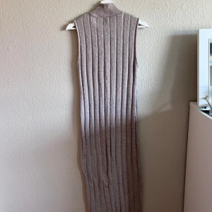 Beige ärmlös ribbad klänning - Säljer en superfin beige ärmlös klänning med ribbad struktur. Klänningen är lång och har en hög hals. Perfekt för både vardag och fest! 💛