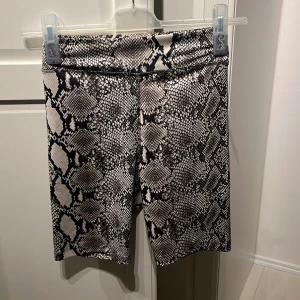 Ormmönstrade shorts från BikBok - Ett par ormmönstrade shorts från BikBok i storlek XS. Shortsen har en tight passform och är tillverkade i ett stretchigt material.