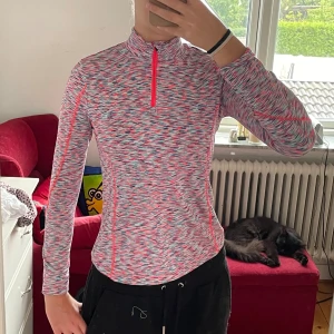 Flerfärgad träningströja från Crivit - Säljer en snygg och bekväm flerfärgad träningströja från Crivit. Tröjan har en halv dragkedja framtill och är perfekt för träning eller andra aktiviteter. Den är långärmad och har en tight passform som sitter bra på kroppen. Materialet är mjukt och varmt.